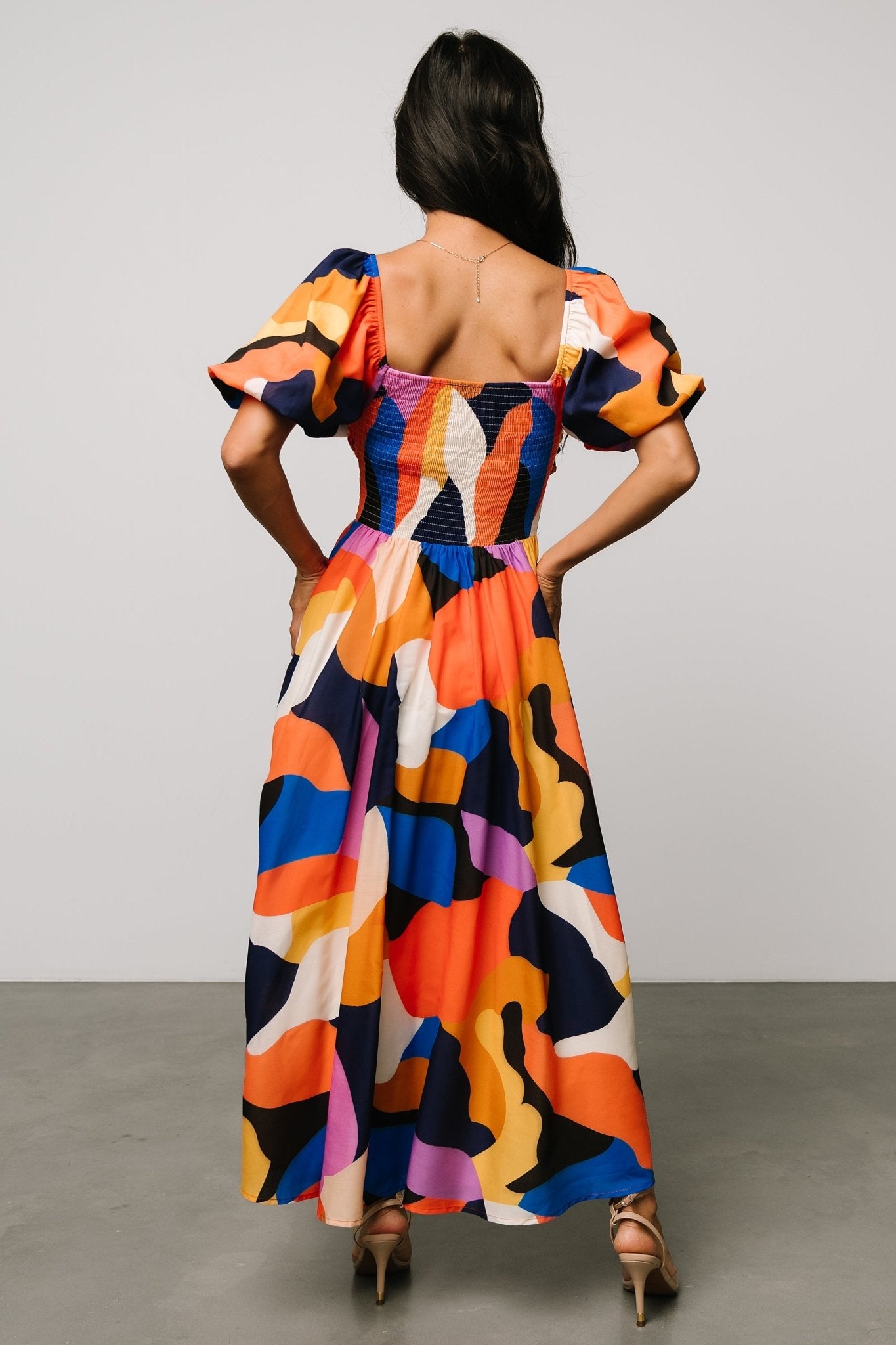 Detail shot of puffed sleeve with elastic at shoulder and woven fabric texture in rust and navy multi abstract print.