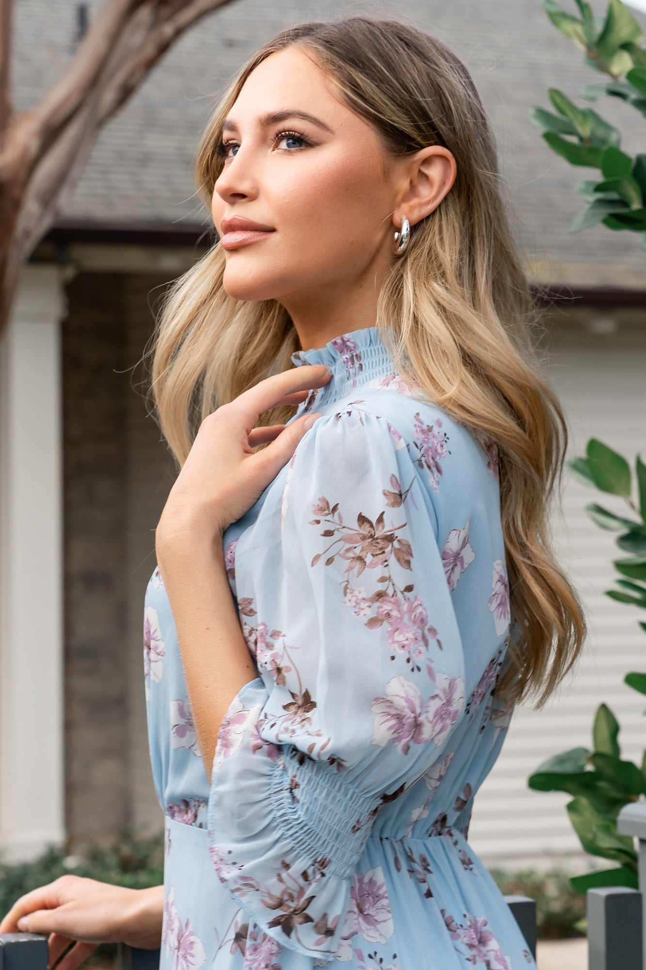 Detail of short sleeves with smocked ruffle cuffs and sheer chiffon fabric, highlighting delicate lavender and off-white floral print.