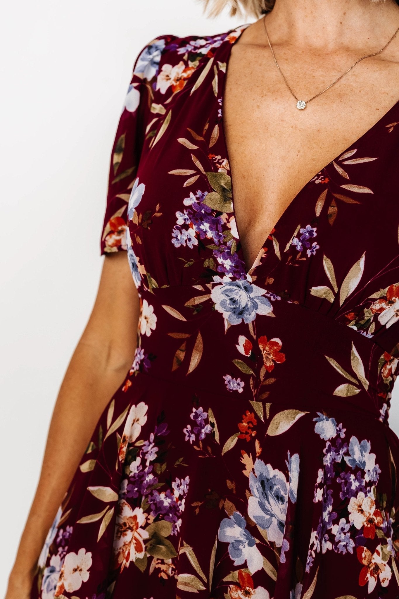 Three-quarter view of mulberry floral maxi showing asymmetrical cascading ruffles, short flowy sleeves, and the dress’s soft drape and print detail.
