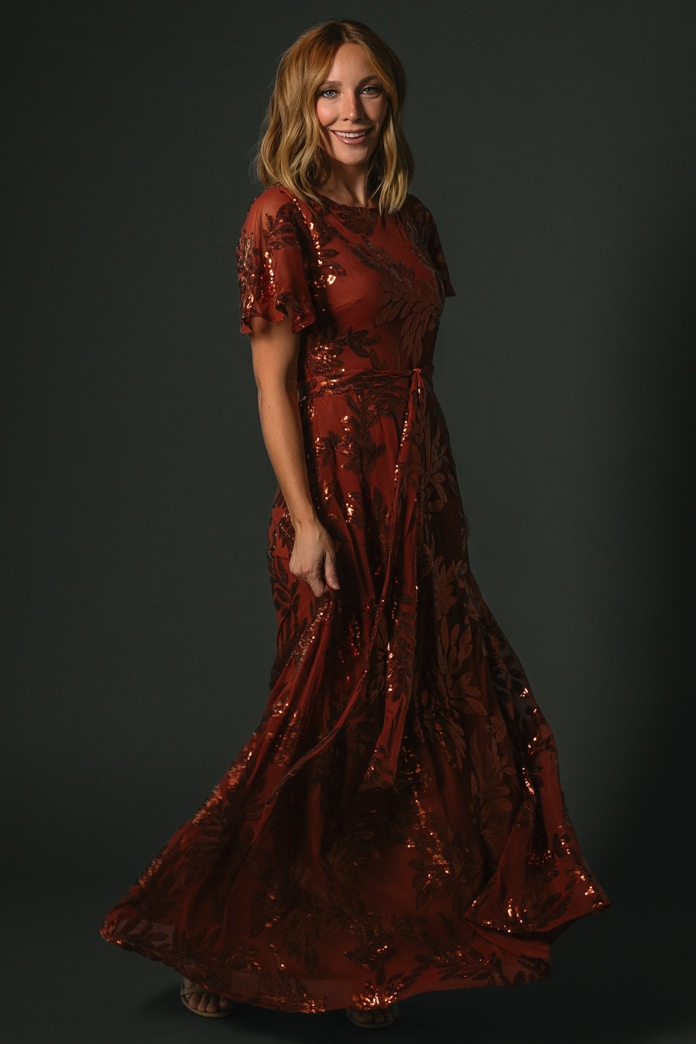 Detail shot of Muse Sequin Maxi Dress cinnamon waist sash and fabric texture emphasizing tailored waist definition and sequin embellishment.