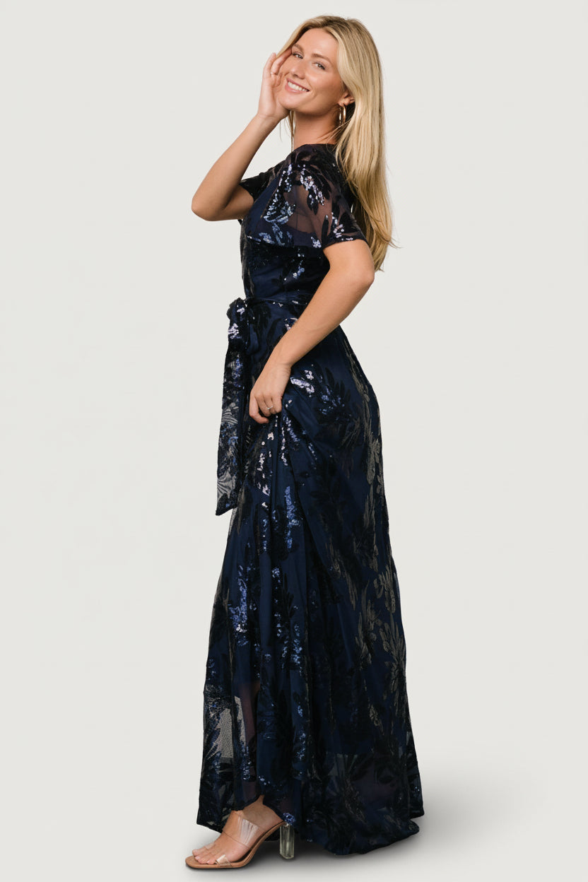 Detail of fabric and sequin application on navy dress, showing leaf motif, stitch placement, and the lined bodice contrasted with sheer sleeves.