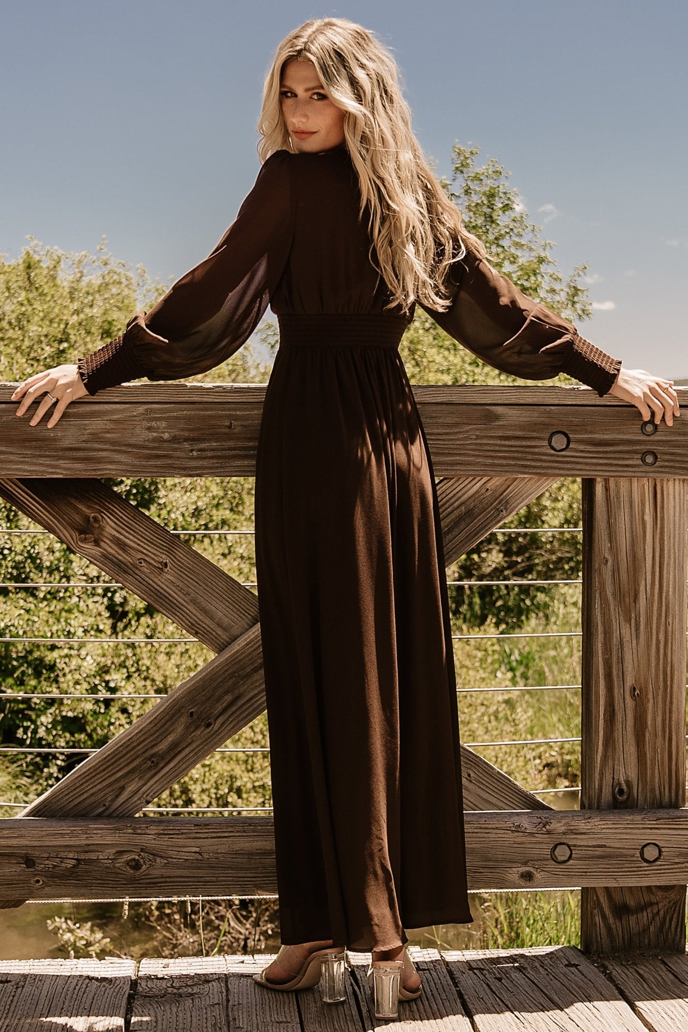Side view of Olivia maxi dress in deep brown on model, showing smocked waist and gentle skirt drape for movement.