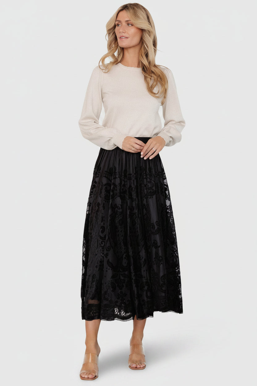 Flat-lay and styling shot of the black velvet-burnout midi skirt focusing on texture, waistband, and the layered construction for wearability.