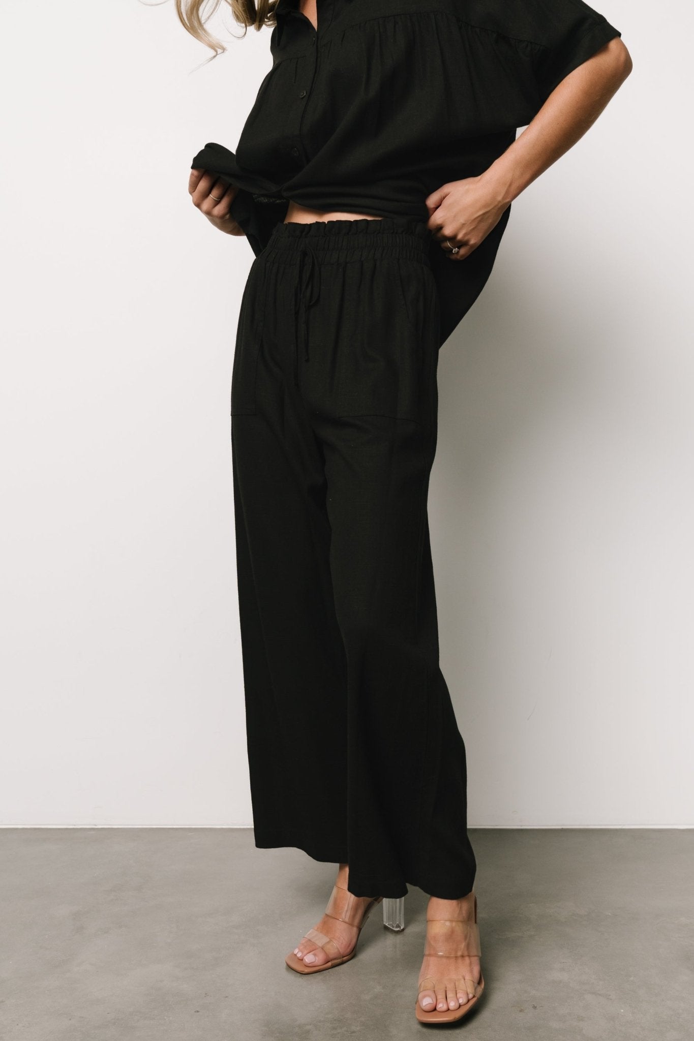 Styled outfit shot of Romy wide-leg black pants paired with tops to show versatile dressing options from casual to dressed-up looks.