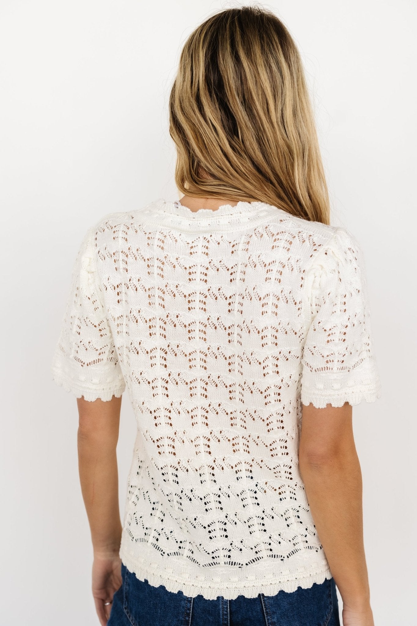Detail shot of the Serenity Knit Sweater Top cream fabric and open-knit holes, emphasizing textured crochet-inspired pattern and scalloped trim.