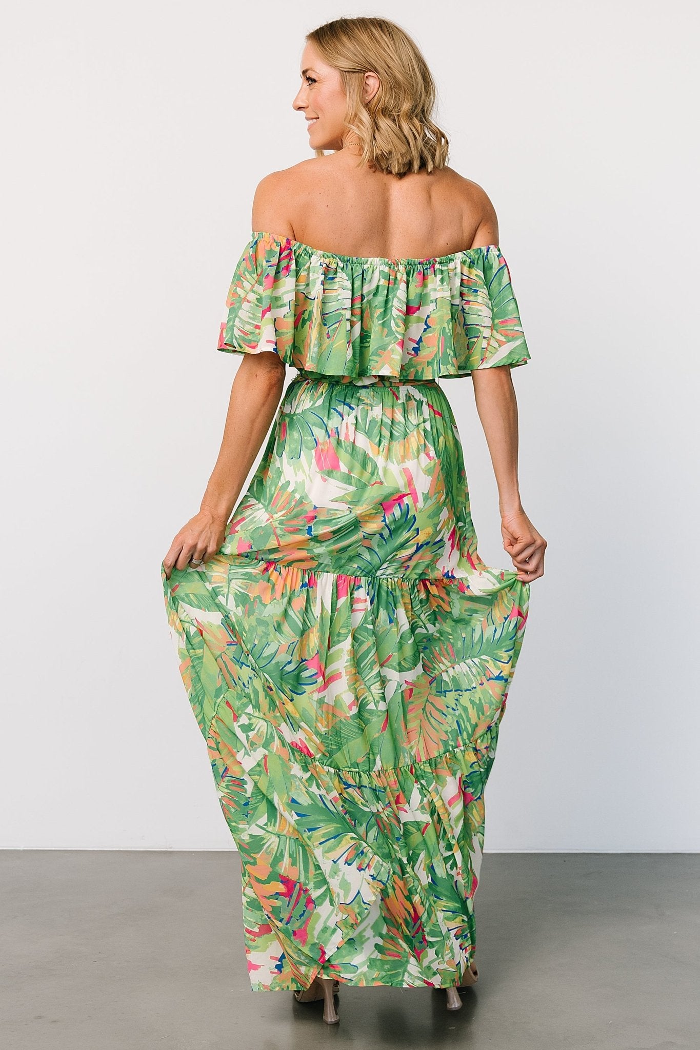 Model wearing Sonoma off-shoulder maxi dress walking, showing natural drape of tiered skirt and elastic waist with self-tie belt.
