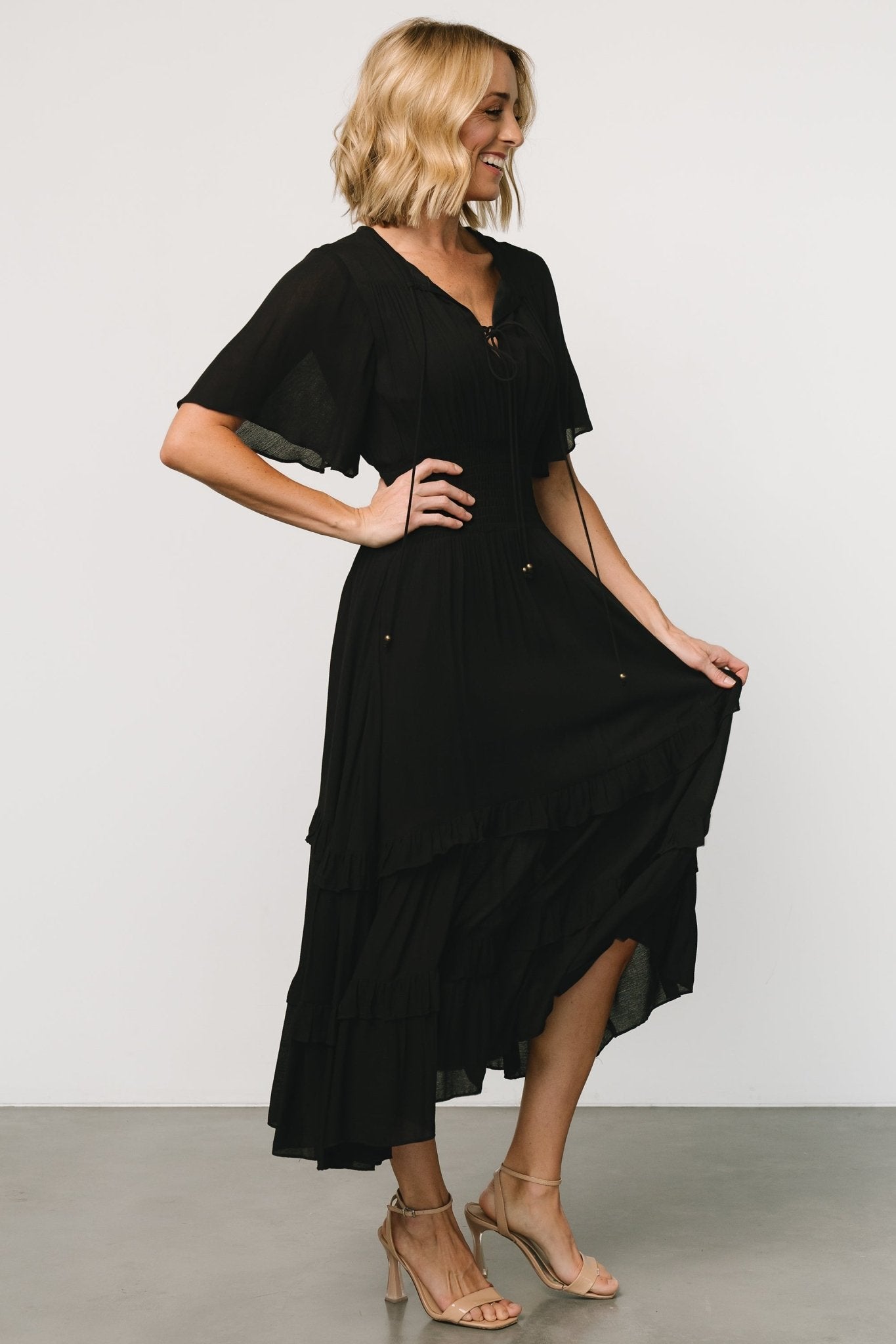 Back view of the black boho midi dress on model, showing the skirt drape and the lining that finishes at mid-thigh for added coverage.