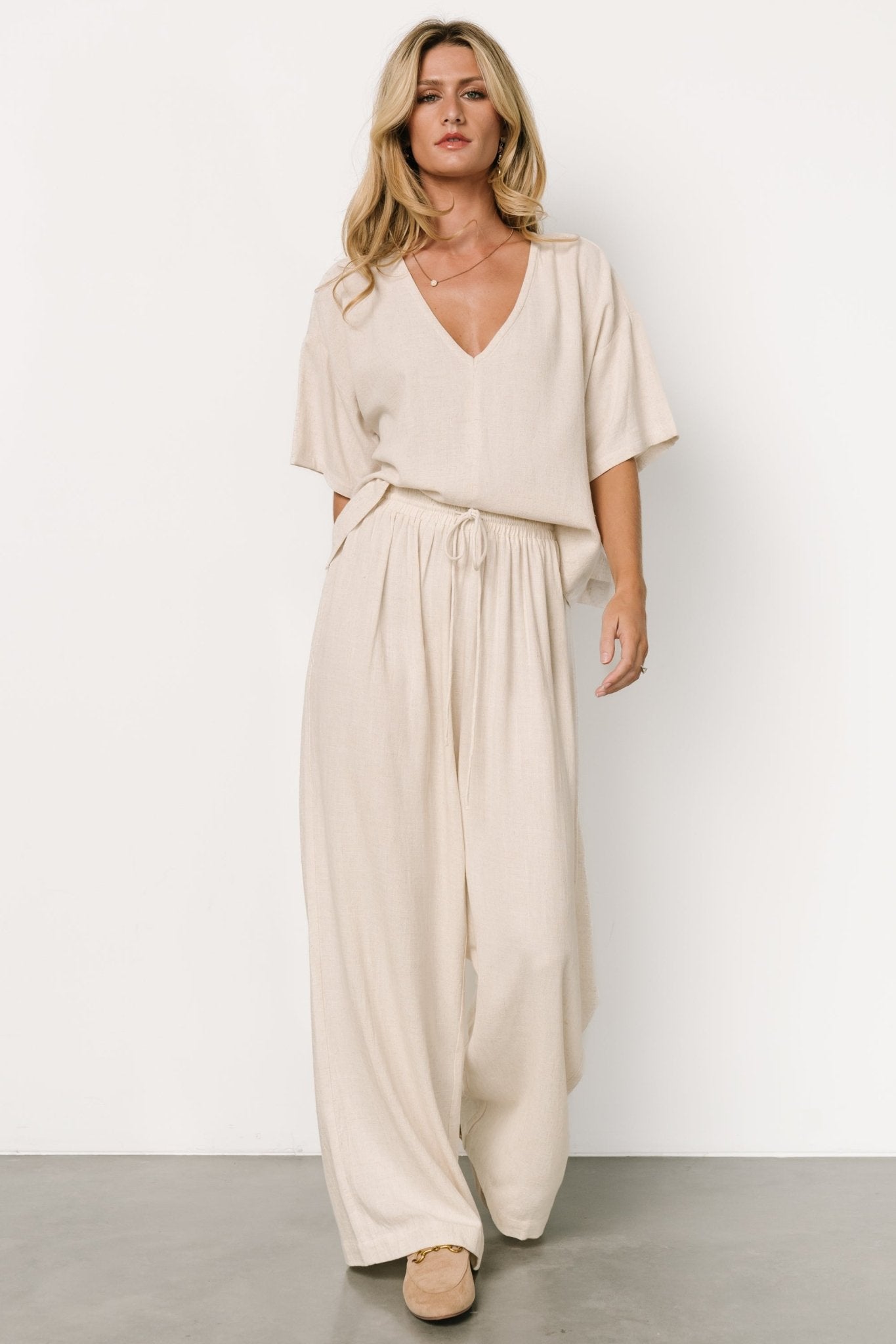 Close-up of top fabric and center detail on natural linen-blend two-piece showing texture and V-neckline with short sleeves.