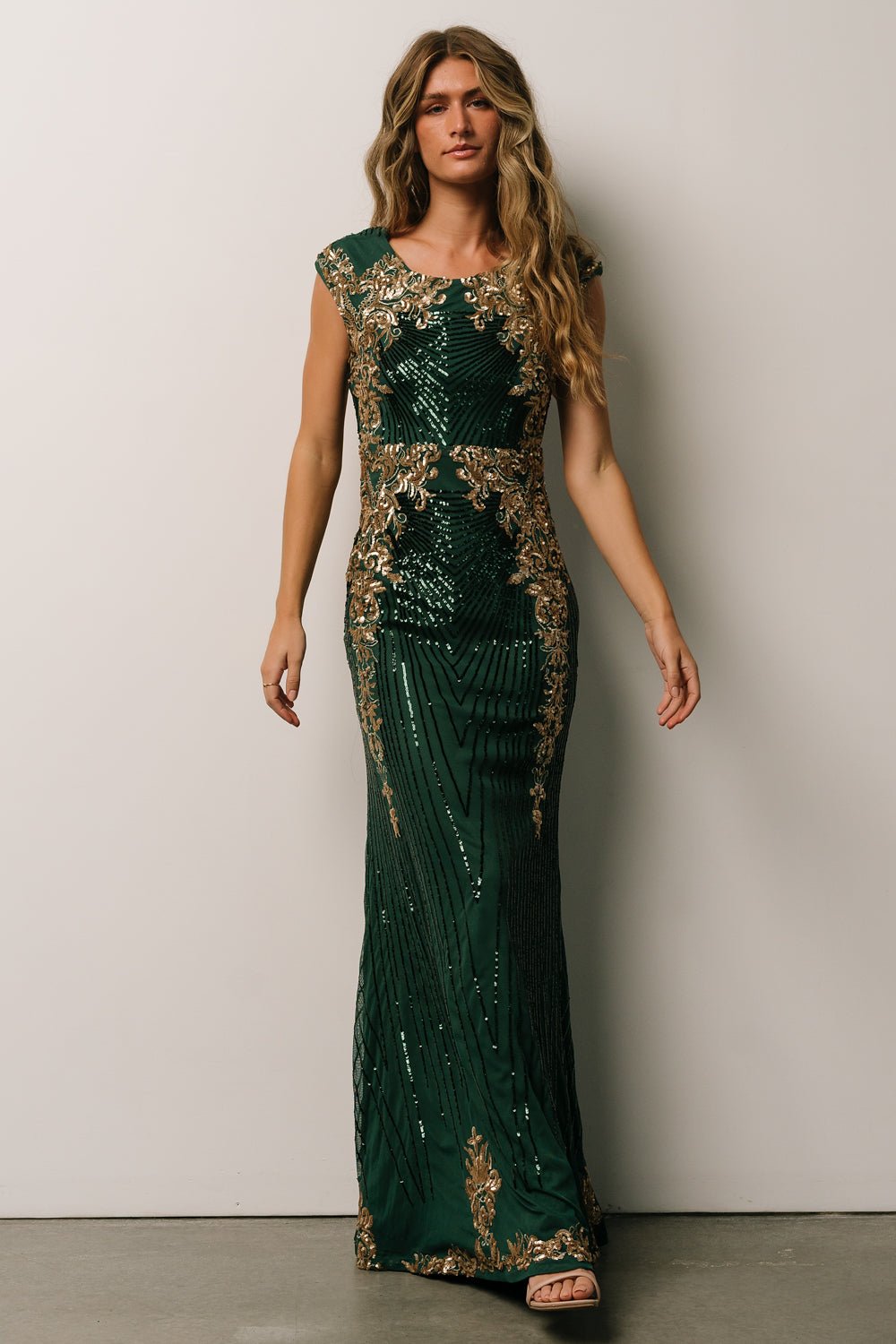 Side profile of Azura green and gold sequin gown emphasizing fitted bodice, cap sleeves, and flowing maxi skirt.