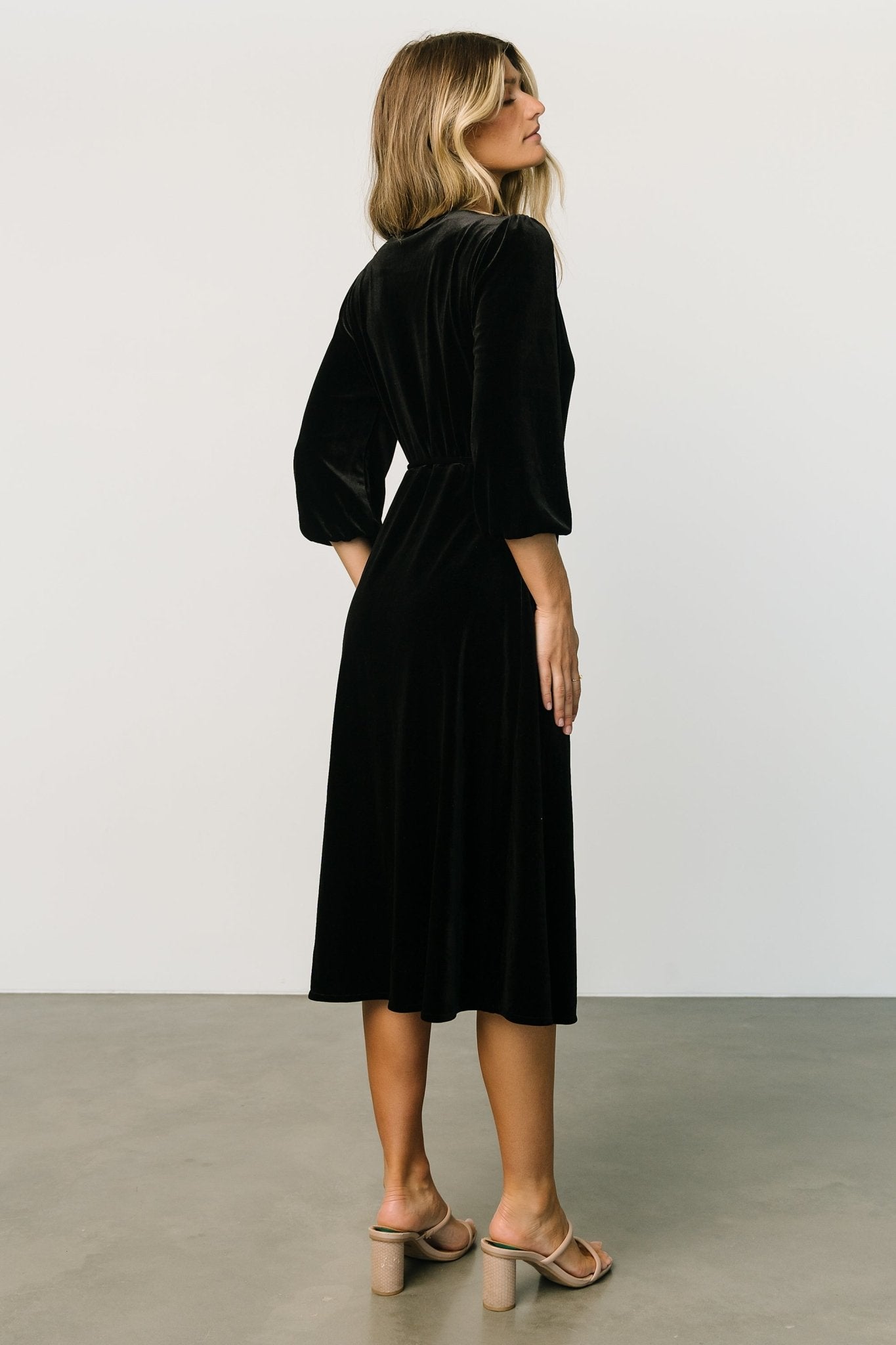 Styled look of the black velvet wrap dress paired with simple shoes, showing overall silhouette, sleeve length and midi hem.