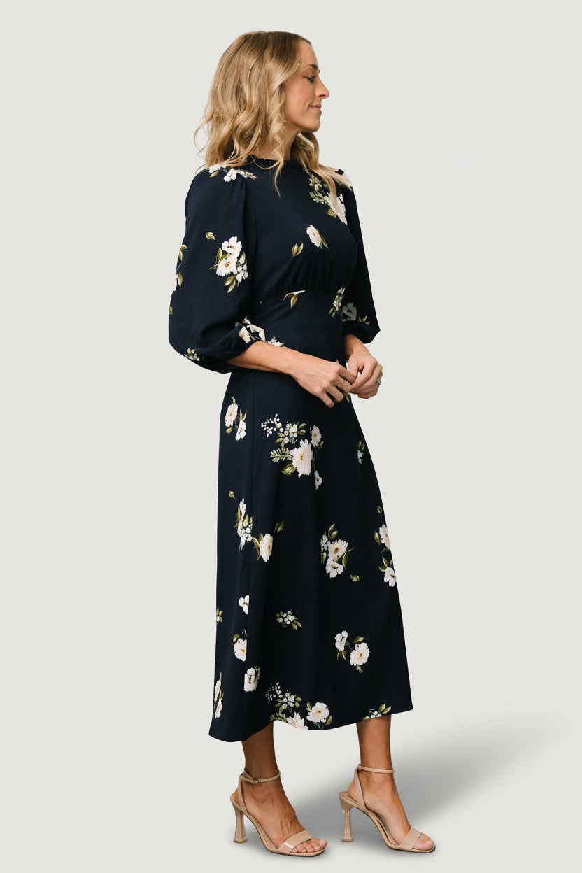 Close-up of ruffled mock neck and ivory floral print on navy fabric, showing texture and neckline shaping details.