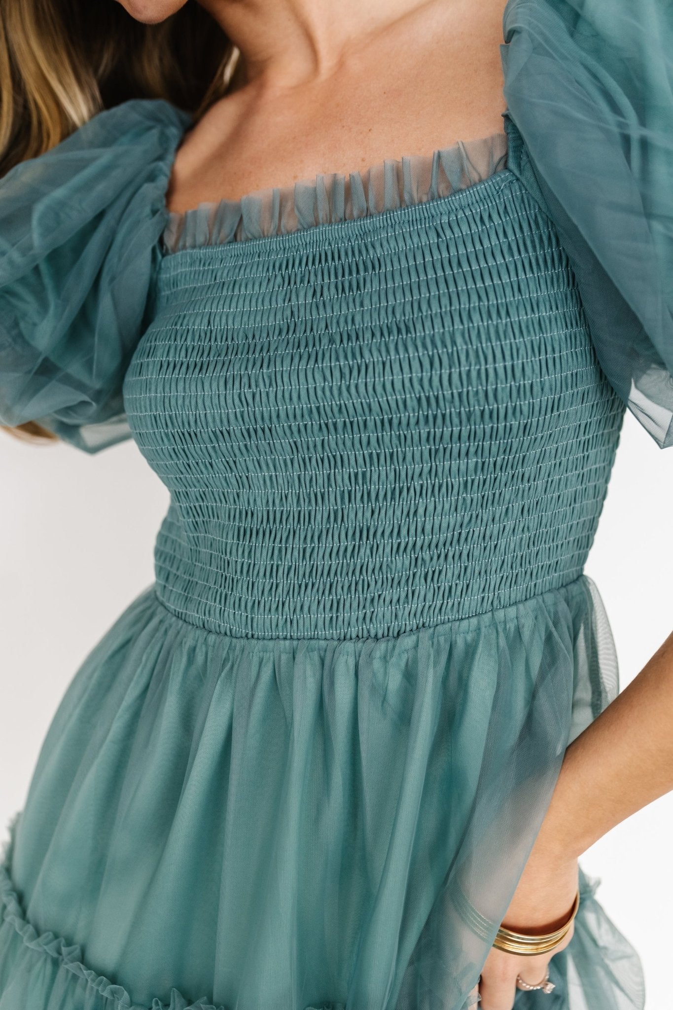 Three-quarter view of eucalyptus tulle midi dress on model highlighting layered tulle overlay, tiered midi silhouette, and soft blue-green color.