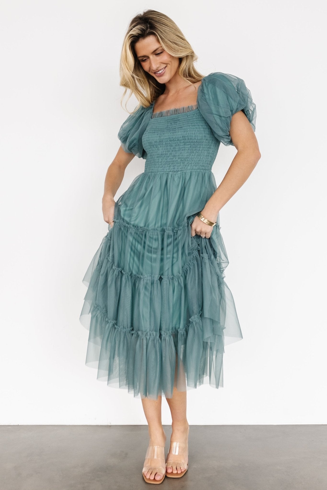 Full-length image of eucalyptus tulle midi dress on model standing, showing elegant silhouette, midi hemline, and layered tulle texture.