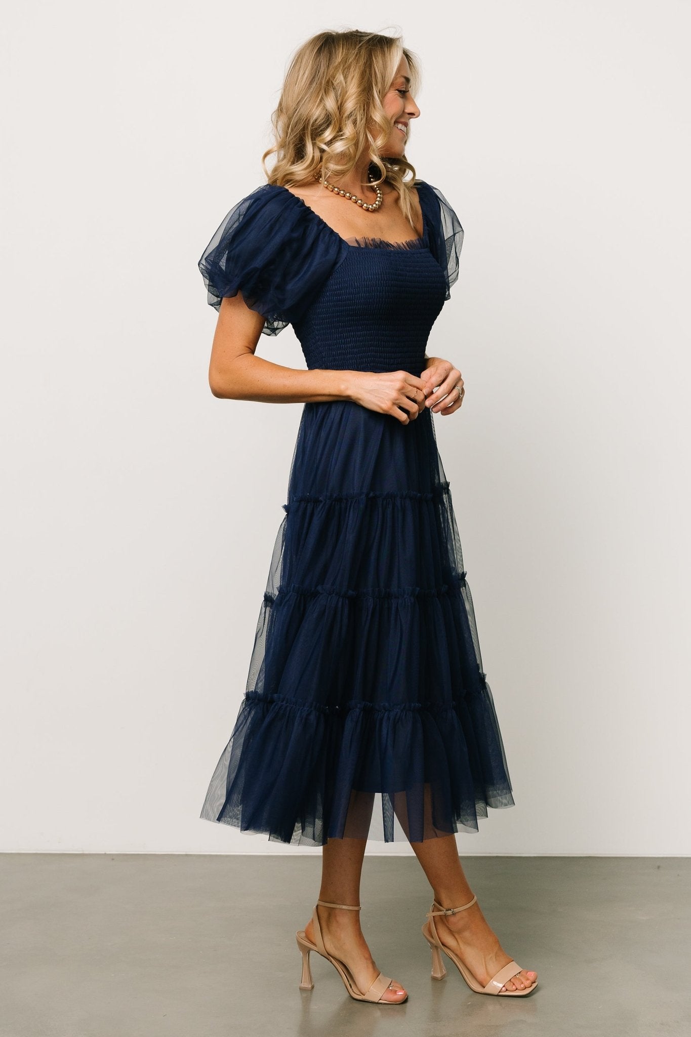 Close-up of the smocked bodice and ruffle square neckline on the navy Liv midi dress, showing texture and stretch of the fabric.