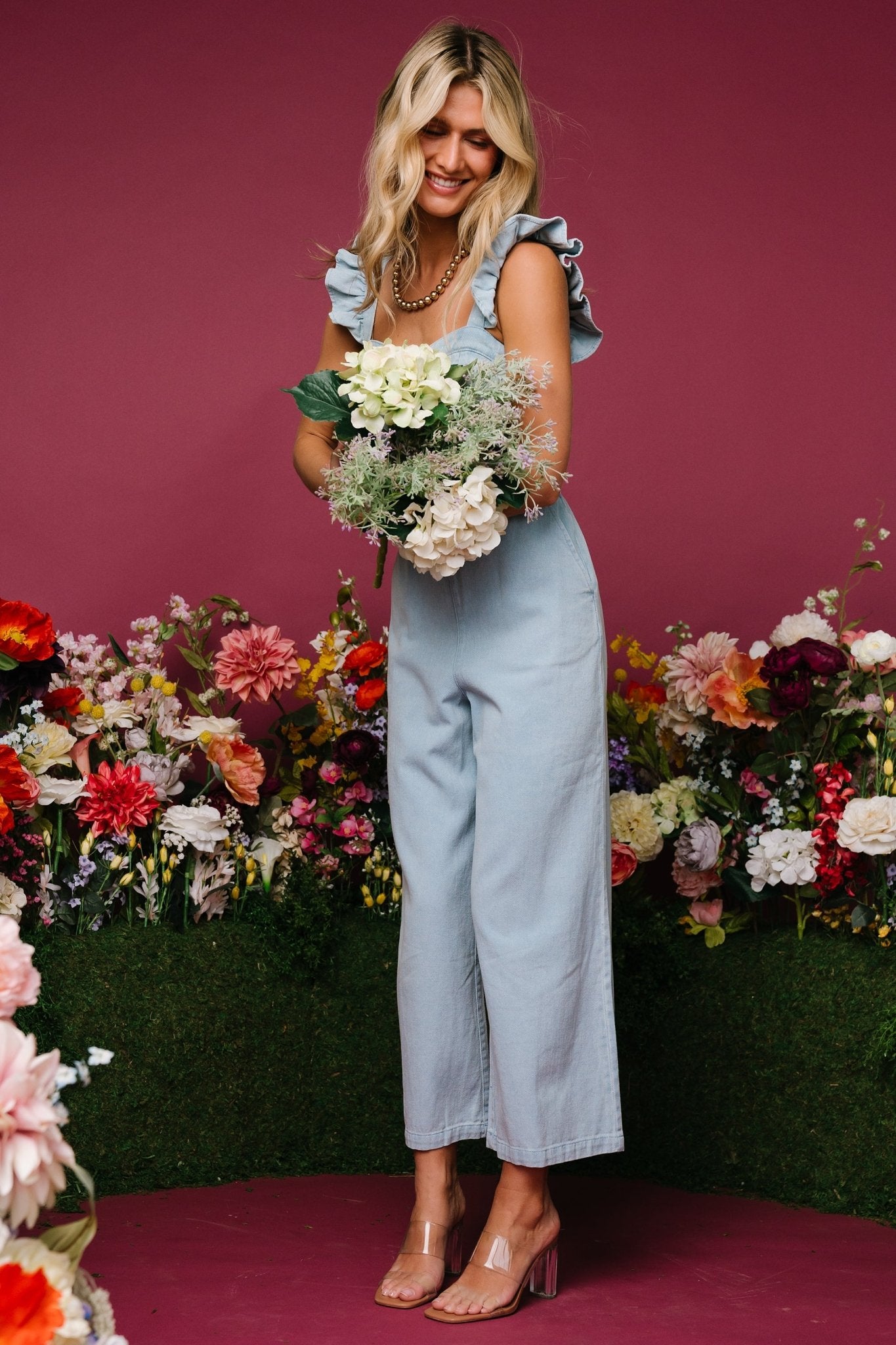 Lifestyle shot of the Madison denim jumpsuit worn with casual shoes, highlighting relaxed styling and wide leg drape.