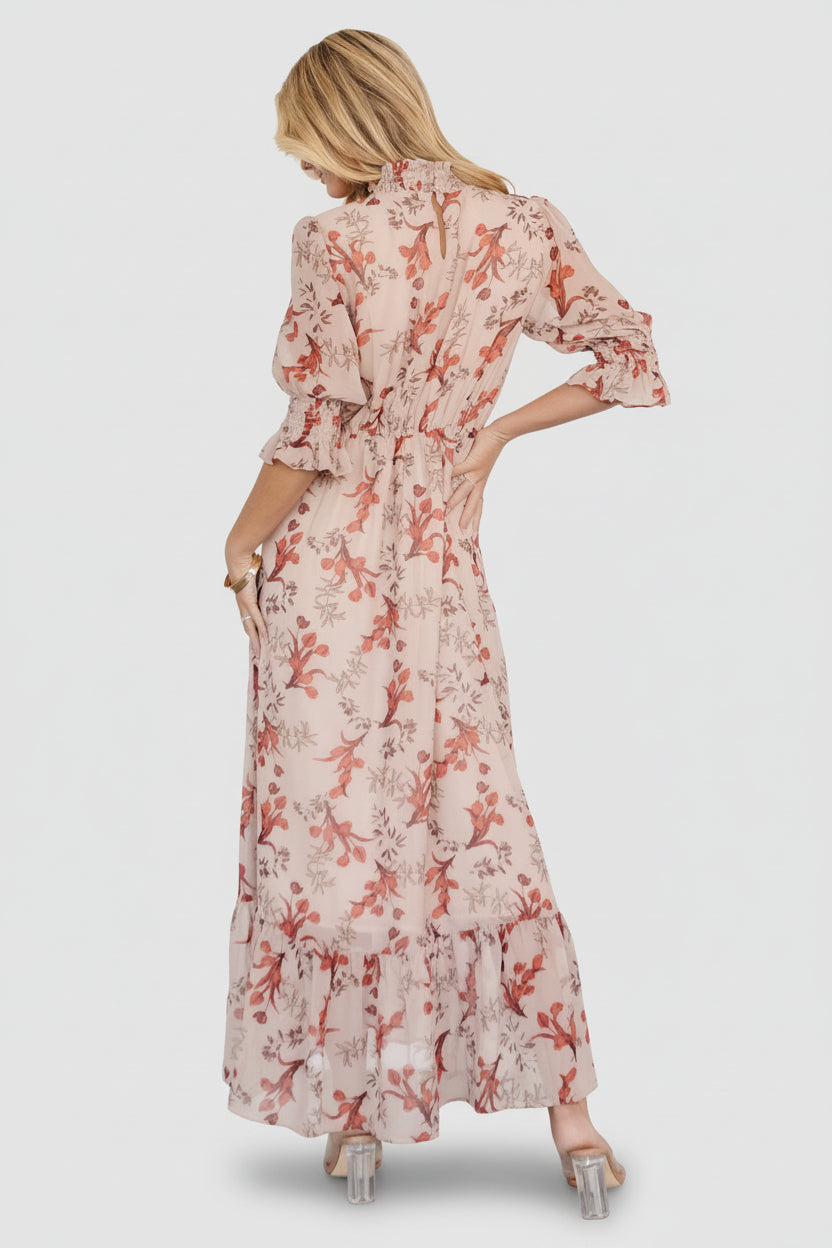 Close-up of smocked mock neckline and pleated front waist on blush floral chiffon fabric, showing texture and stitching details.