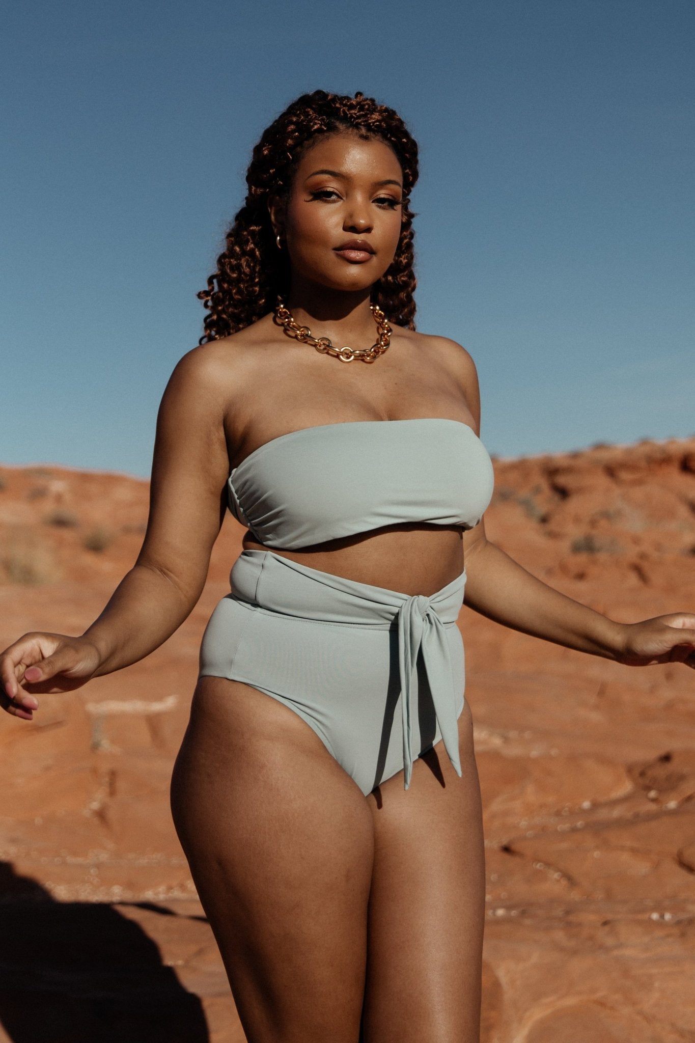 Model wearing Milos sage bandeau bikini top, close-up of neckline and soft stretch fabric highlighting subtle sage color and fit.
