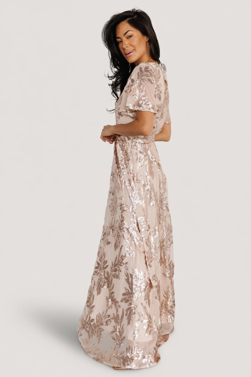 Studio image of the dress on a model highlighting the round neckline, short sheer sleeves, and the elegant silhouette created by the sash.