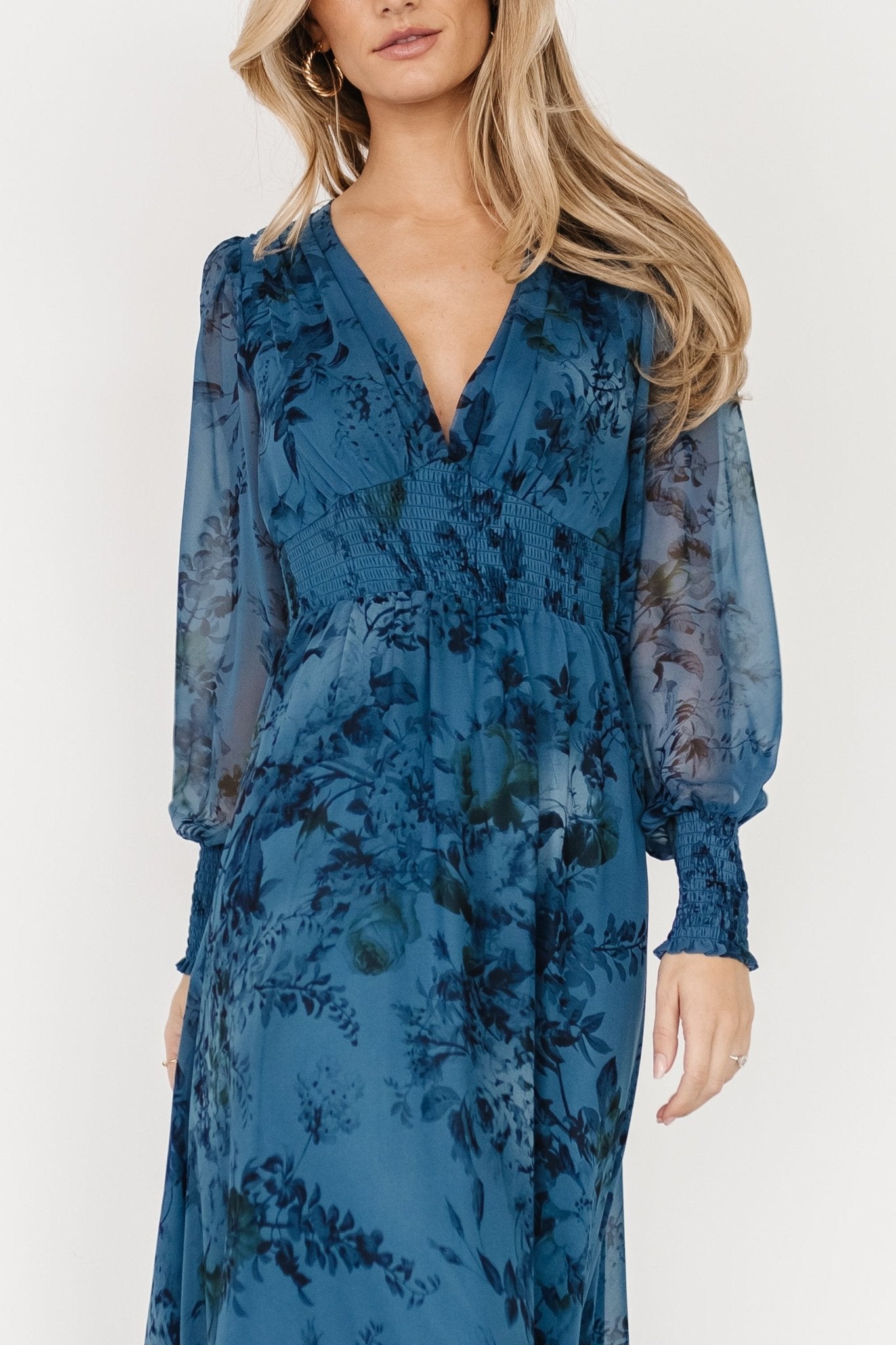 Three-quarter view of the chiffon maxi dress highlighting the smocked waist, flowing skirt and deep V-neck silhouette.
