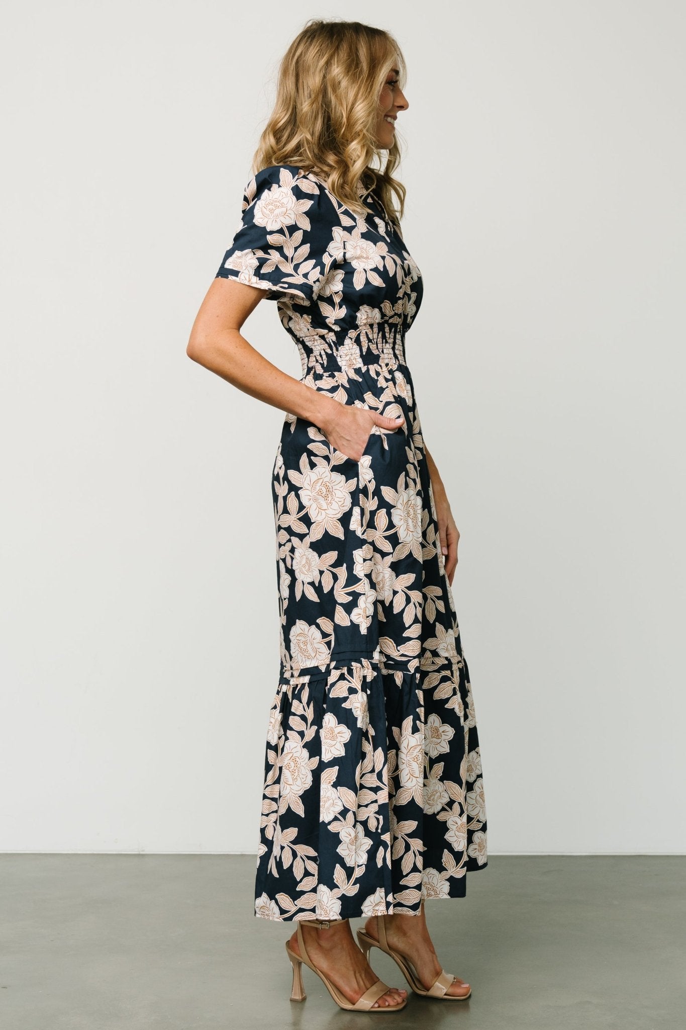 Back view of Vera Maxi Dress in navy floral highlighting subtle layered back detail, smocked waistband and the full maxi silhouette on model.