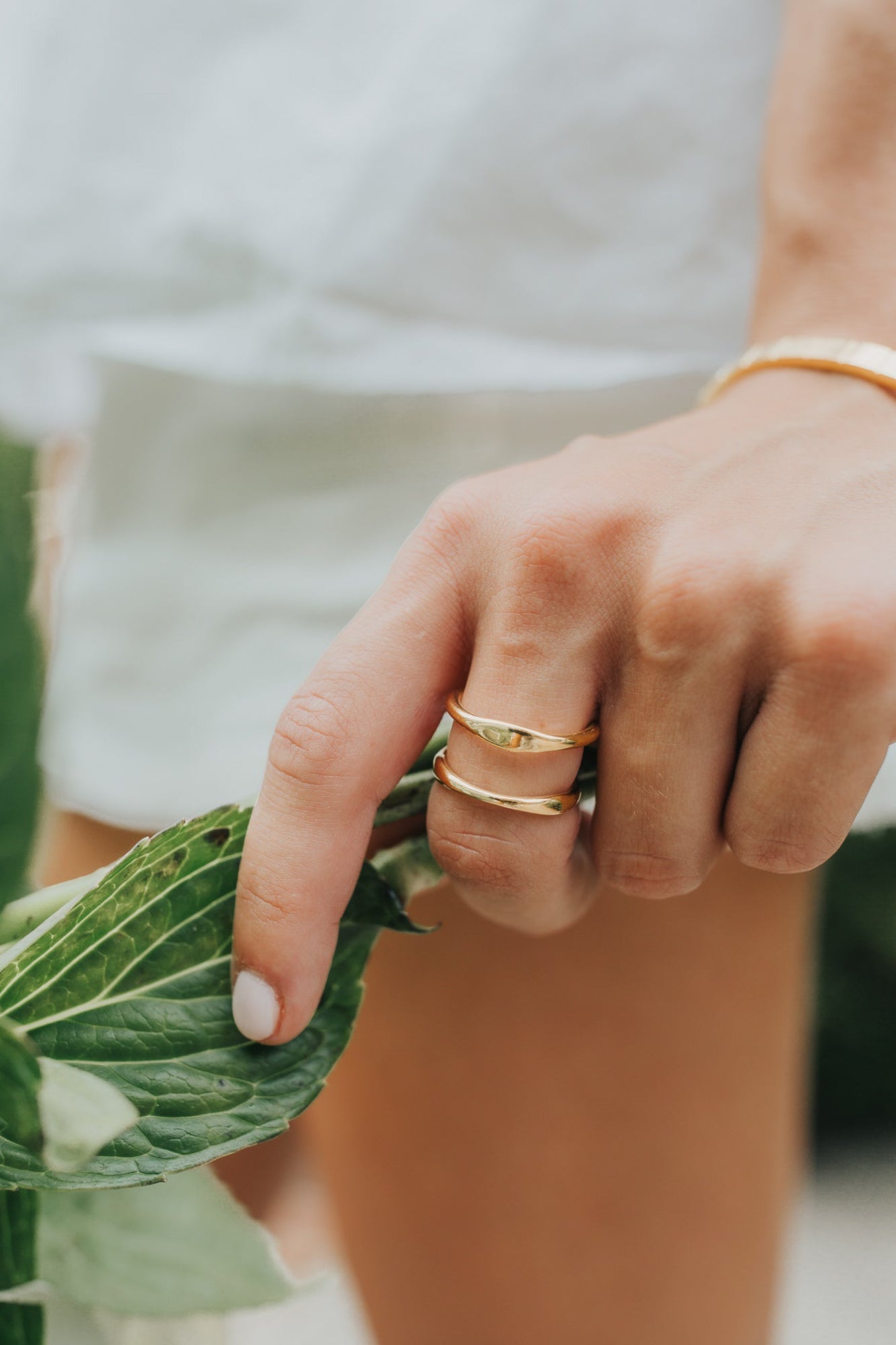 Flat lay of the Florence ring with complementary bracelets and necklaces, demonstrating styling options and polished gold finish.