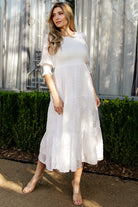 Flat-lay of off-white Nellie Smocked Midi Dress highlighting round neckline, puffed sleeves, smocked bodice and tiered skirt silhouette.