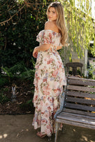 Full-length image of the multi floral maxi dress tucked at the smocked waist, showcasing four-tiered skirt and graceful hem movement.