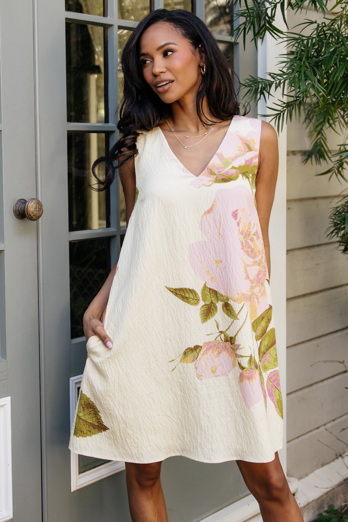 Close-up of the dress fabric highlighting the pale yellow base, pink and green floral pattern, and crinkled weave.