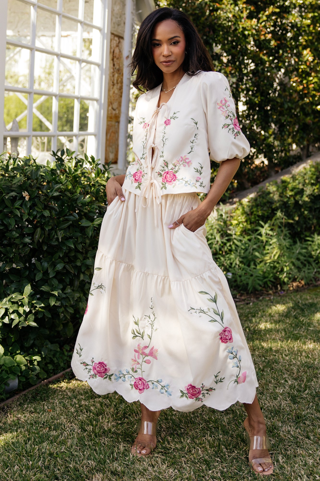 Front view of model wearing Josephine cream floral two-piece set, tie-front cropped top with puff sleeves and high-rise tiered skirt visible.