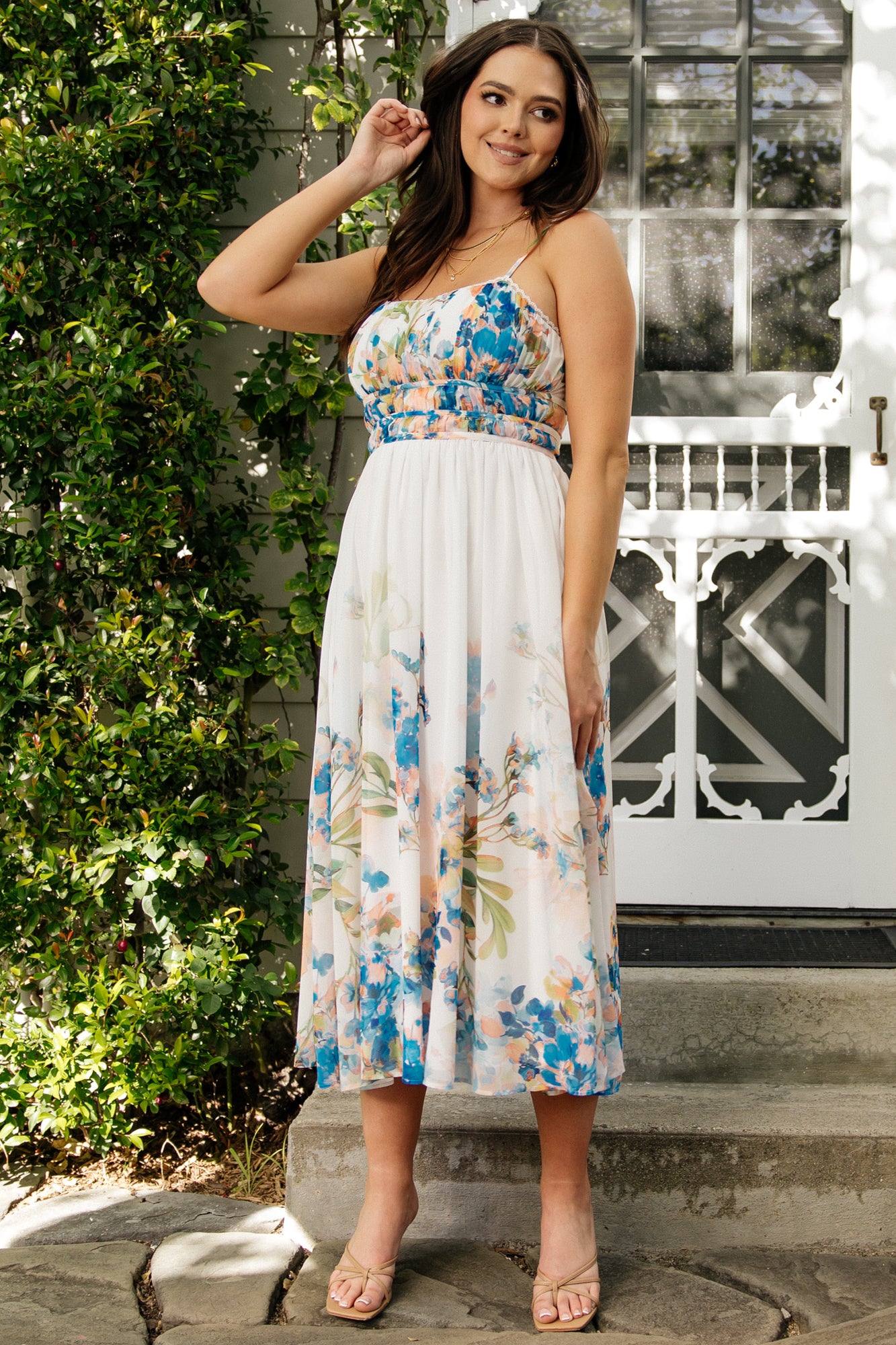 Front full-length view of Marceline midi dress in white and blue floral chiffon with lace-trim V-neck and a flowy midi skirt showing natural movement.
