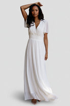 Front view of Birdie Chiffon Maxi Dress in white on model, showing V-neck, flutter sleeves, smocked waist and flowing skirt, full-length.