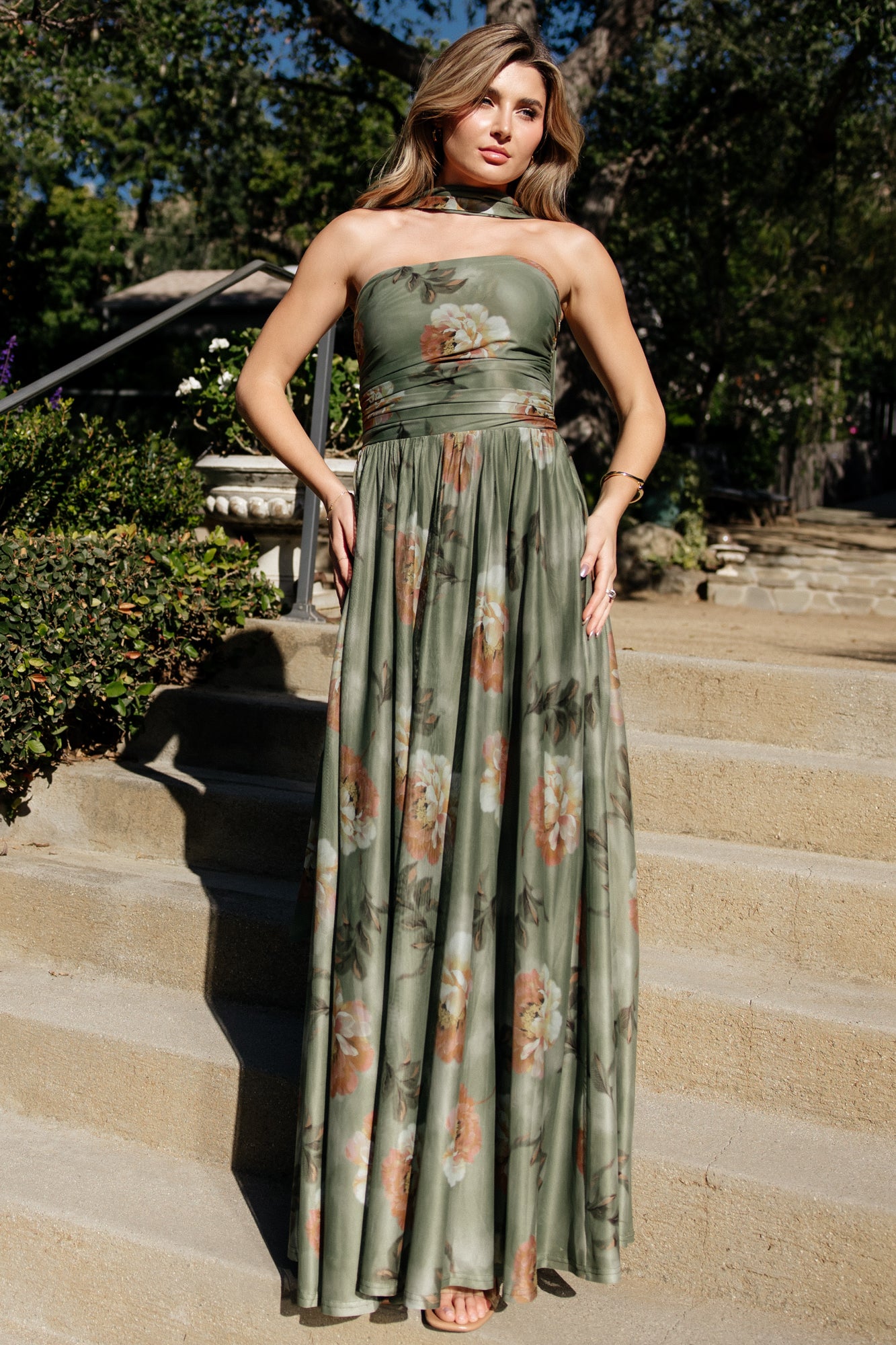 Front view of dark sage floral strapless maxi dress on a model, showing fitted bodice, flowing skirt, and included neck scarf for styling.