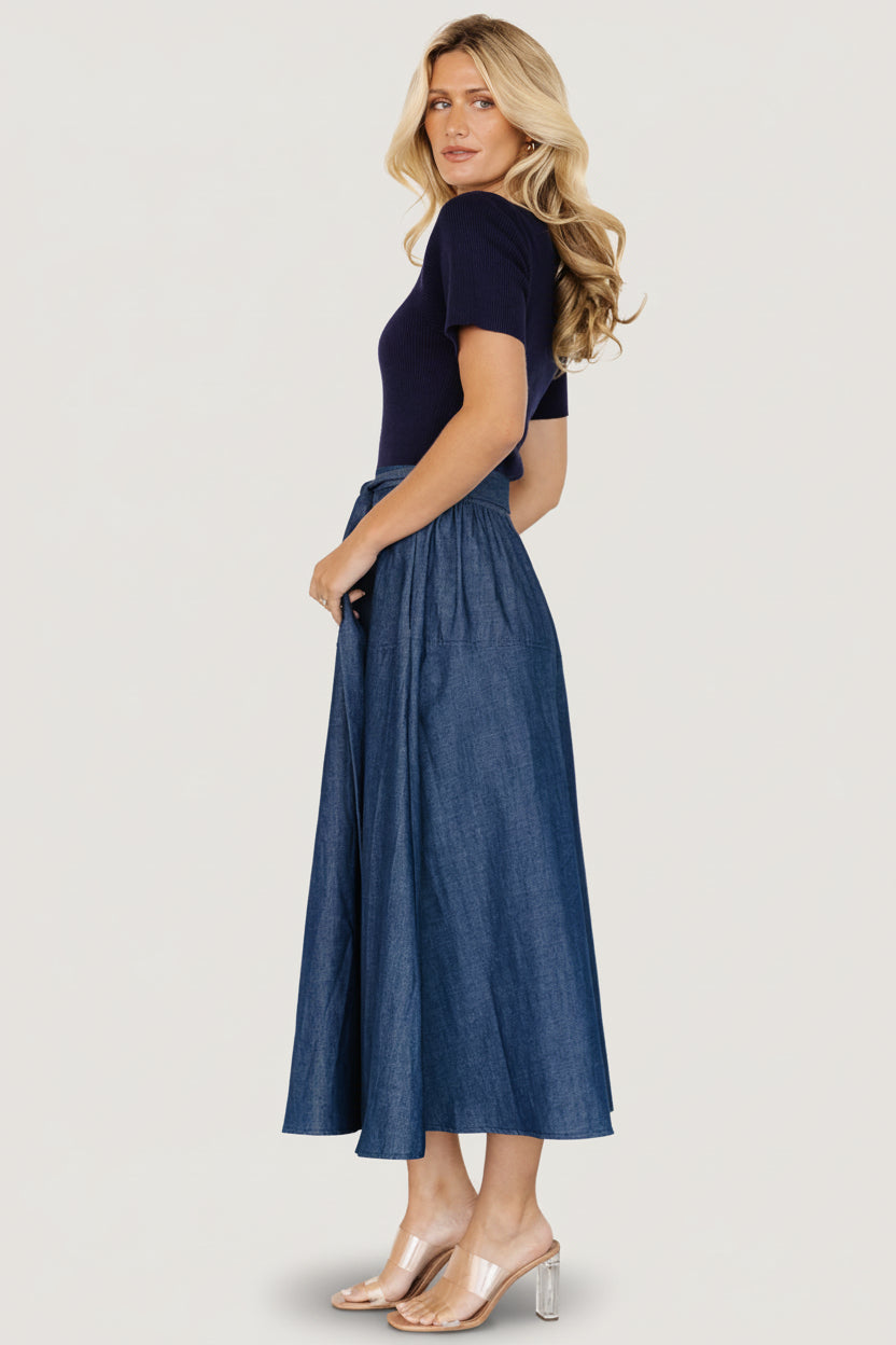 Back view of Olina midi dress on model showing skirt drape and waist tie tied at the rear for a fitted look.