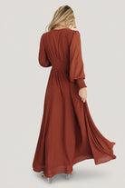 Studio flat-lay of the Olivia Maxi Dress in cinnamon on a neutral background showing full silhouette, maxi length and long sleeve details.