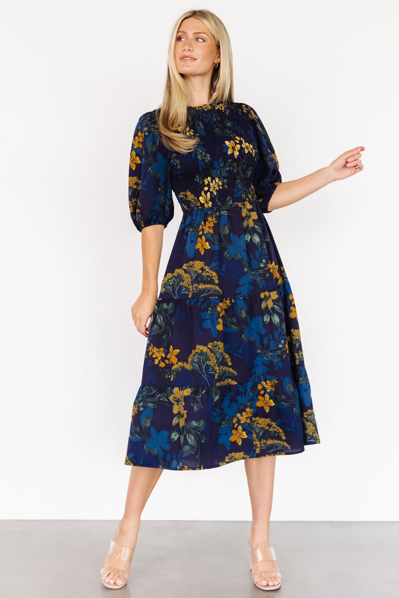 Three-quarter view of the navy Lena Tiered Midi Dress highlighting the elasticated waistband, mid-length sleeves with elastic cuffs, and floral print details.