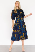 Three-quarter view of the navy Lena Tiered Midi Dress highlighting the elasticated waistband, mid-length sleeves with elastic cuffs, and floral print details.