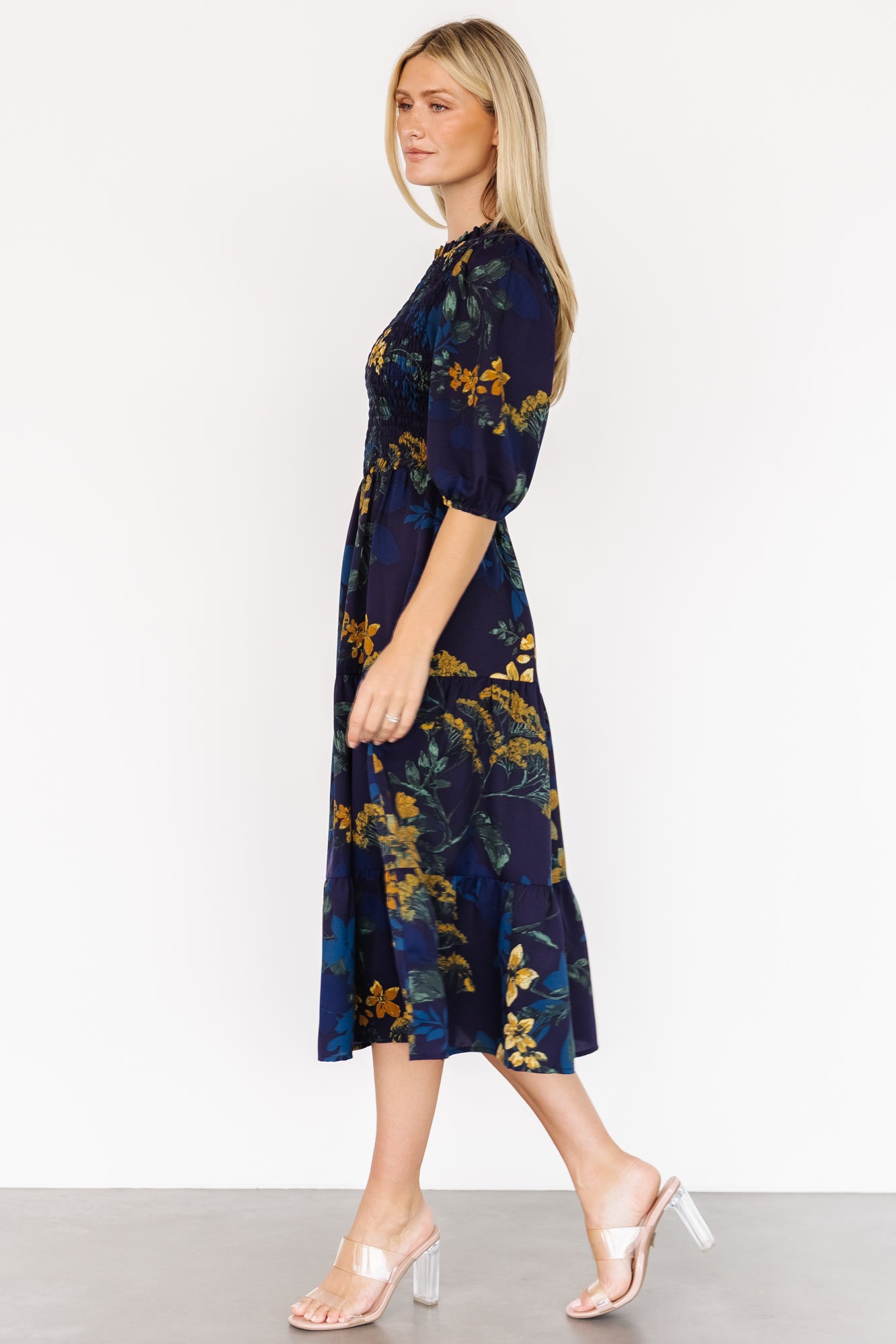 Full-length shot of the Lena Tiered Midi Dress in navy with gold floral pattern, showing silhouette, midi length and tiered movement on model.