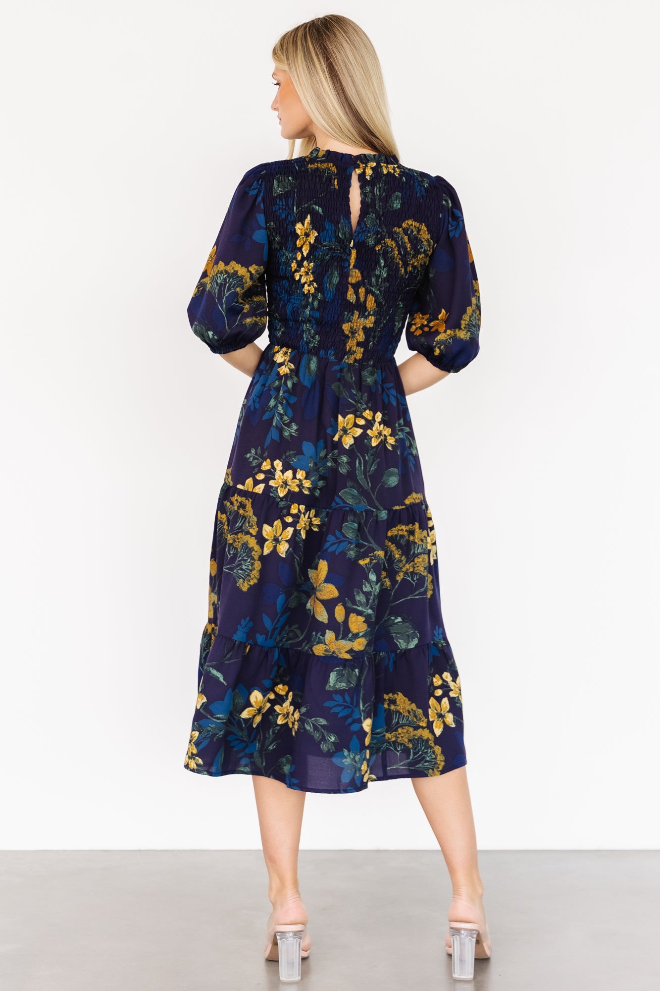 Close-up of the gold floral print and smocked bodice on the Lena Tiered Midi Dress, showing fabric texture and stitch detail on chiffon.