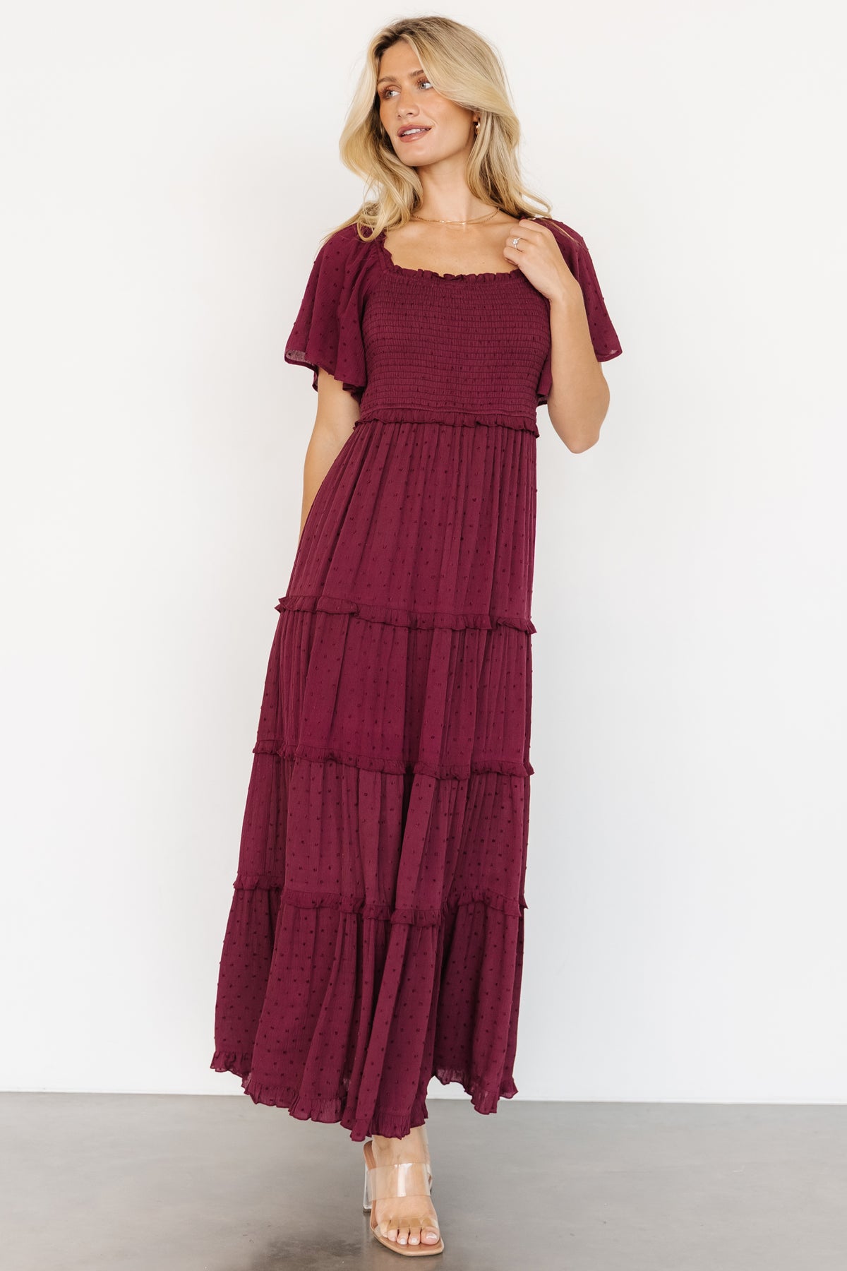 Front view of model wearing Lenora Smocked Dotted Maxi Dress in wine, showing square neckline, smocked bodice, and flutter sleeves.