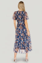 Three-quarter view of dark blue Mara dress highlighting the round neckline, button-keyhole back closure, and smocked stretch bodice.