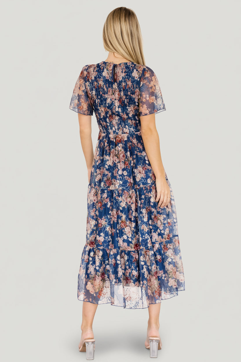 Three-quarter view of dark blue Mara dress highlighting the round neckline, button-keyhole back closure, and smocked stretch bodice.