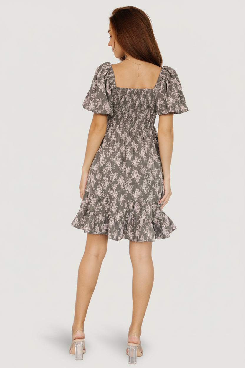 Close-up of the smocked bodice and decorative bow on the Anastasia Bow Short Dress in Dusty Olive Print, with visible floral pattern and texture.