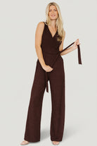 Front view of model wearing Natasha Jumpsuit in espresso, showing surplice neckline, adjustable side tie and wide-leg silhouette in crepe fabric.