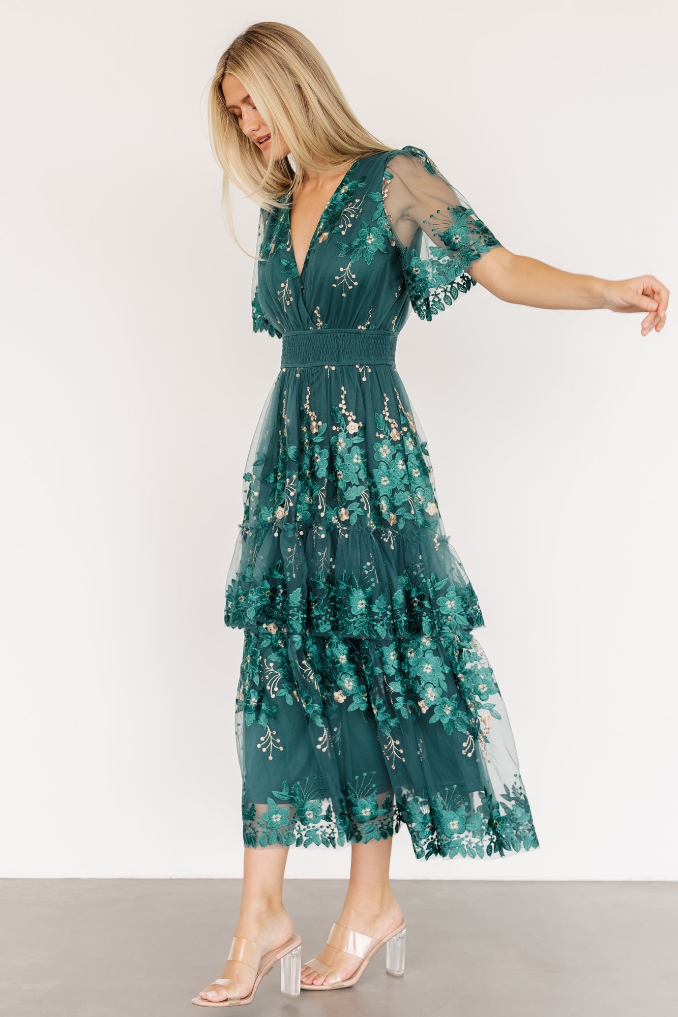Fabric detail shot of emerald tulle and embroidered florals with close-focus on threadwork, scalloped sleeve edge and lining contrast.
