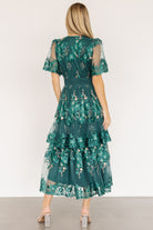 Side view of Lotte midi dress showing scalloped sheer short sleeve, smocked waistband and gentle flare of the tiered skirt.
