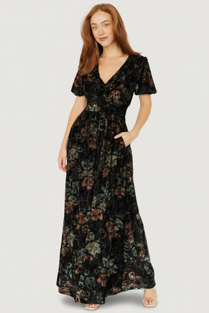 Three-quarter view showing embossed velvet floral texture and gathered waist detail on the Leslie Velvet Maxi Dress; side pockets visible.