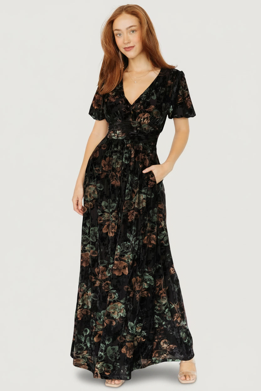 Three-quarter view showing embossed velvet floral texture and gathered waist detail on the Leslie Velvet Maxi Dress; side pockets visible.