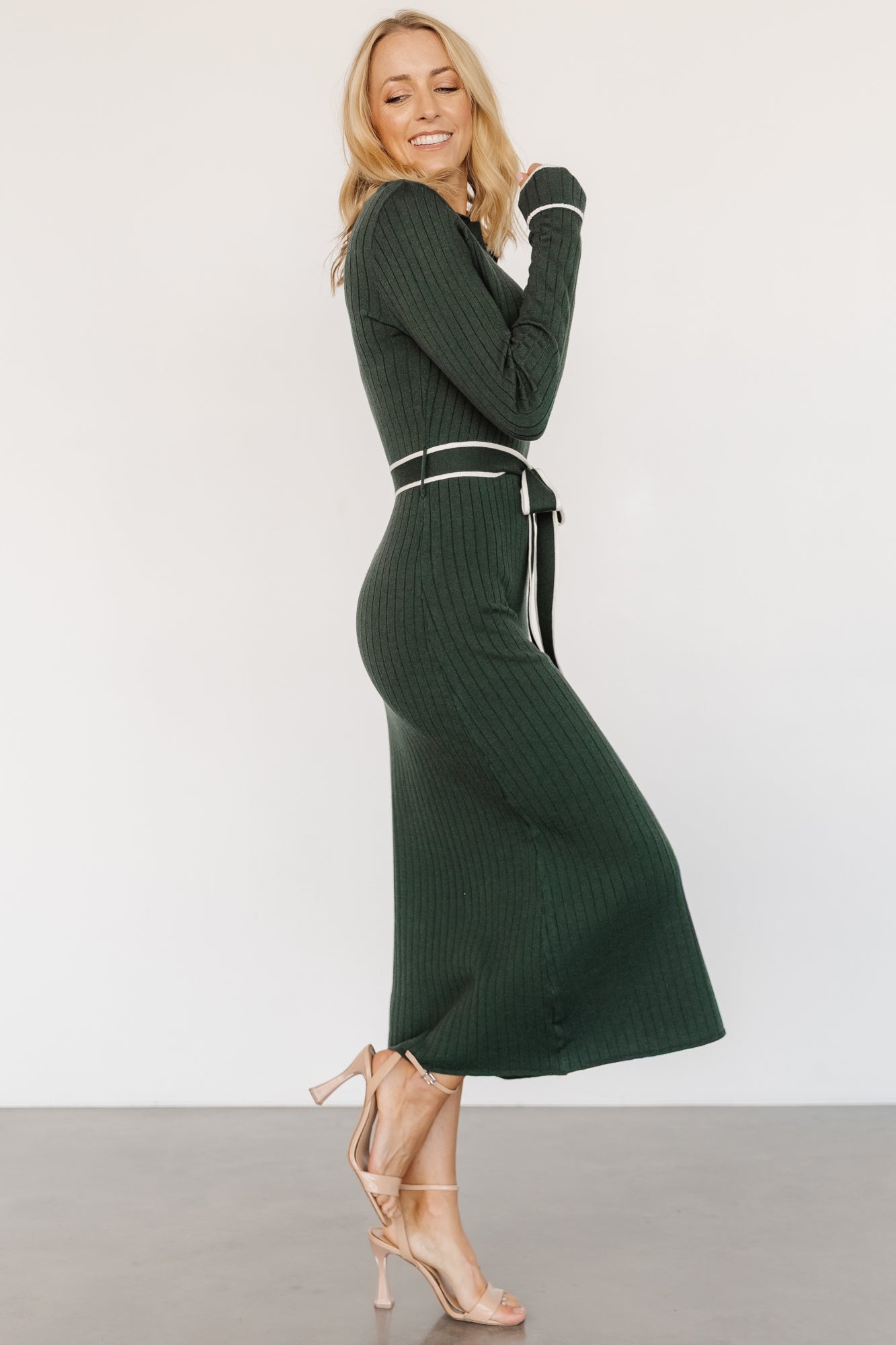 Back view of the Lark midi sweater dress in green on model, showing fitted shape through the waist and hips and the dress length to mid-calf.