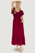 Front view of Monica Smocked Maxi Dress in mulberry showing V-neck, smocked bodice, flutter sleeves, and flowing tiered skirt.