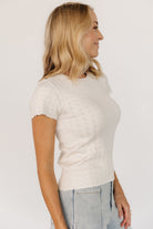 Lifestyle shot of the ivory Penny Pointelle Top paired with high-rise jeans, illustrating a casual, everyday outfit.